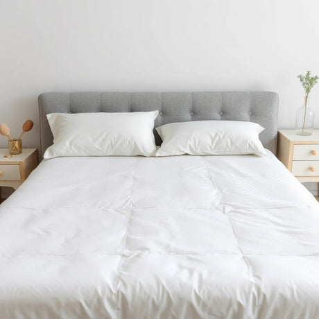 Neatly made bed with a breathable hypoallergenic mattress protector covering the mattress