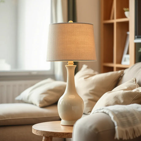 Ceramic table lamp on a side table with a warm, softly glowing fabric shade