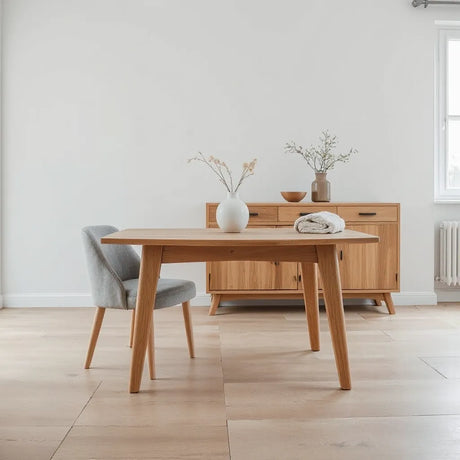 Light oak dining table and linen chair in a bright neutral living room with natural materials