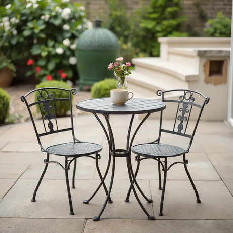 Metal bistro set with round table and two chairs on a patio with soft garden background
